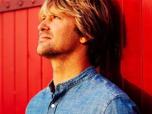 Portrait de profil de Tom Frager fond rouge